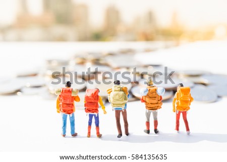 Miniature people: Small backpackers walking on coins road with cityscape background. Business agency marketing and Travelling concepts.