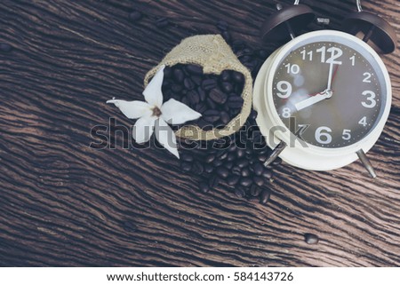 Vintage brown clock face and and coffee bean in sack fall on wooden table outdoor background.Coffee break for relax time concept- Vintage effect style pictures