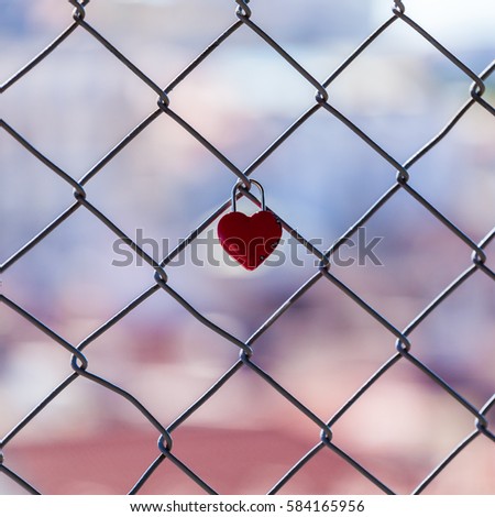 Padlock in the form of heart hanging against a blurred cityscape