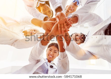 Many happy doctors stack hands together as team for motivation Royalty-Free Stock Photo #584171068