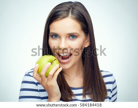 Teenager girl with dental braces bites apple. Smiling girl portrait isolated on white.