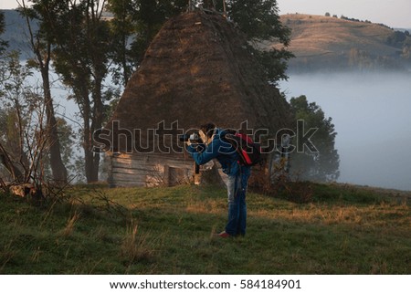 female photographer at sunrise, misty mountains