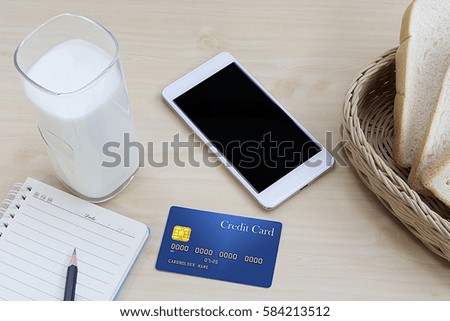business work on wooden table milk with cut bread, credit card and mobile phone