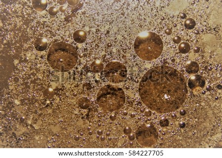 Drops of scented oil floating on hot water in colored background texture. The focus ranges from central sharp with gradual merging of bubbles to the outside of the macro photo.