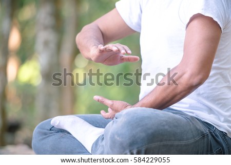 Young man practicing traditional Tai Chi Chuan, Tai Ji  and Qi gong in the park for healthy, traditional chinese martial arts concept on natural background . Royalty-Free Stock Photo #584229055