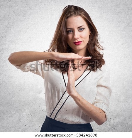 Beautiful brunette girl making time out gesture on textured grey background