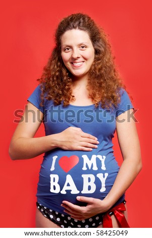 Portrait of pretty pregnant woman in blue tanktop and polka-dot panties looking at camera