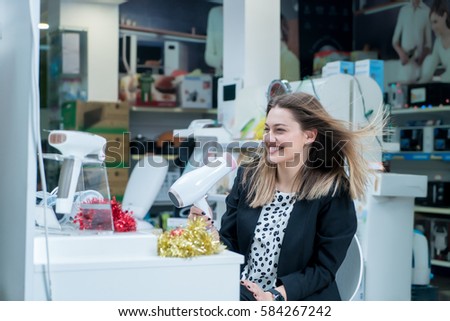 Haircare. Beautiful long haired woman drying hair in electronic store