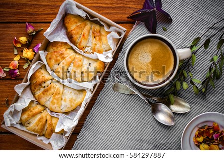 Croissants packed and cup of coffee on wooden table decorated with home stuff
