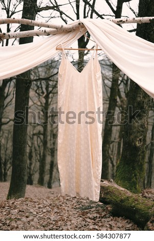 Wedding dress hanging on the decoration arcs front of forest