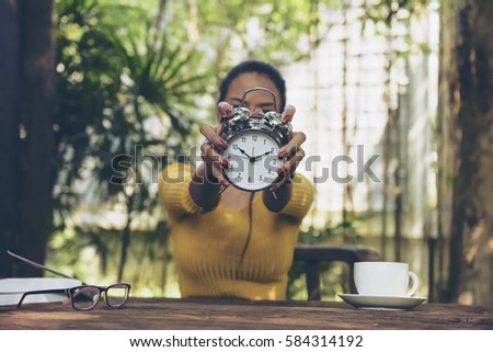 Portrait of beautiful black hair woman giving  Vintage antique clock  in the back garden coffee shop.Happy education concept.Everywhere make money.