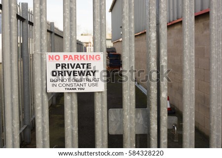 Set of locked security gates with a no parking sign at an industrial or commercial premises