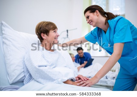 Nurse consoling a patient in ward at hospital Royalty-Free Stock Photo #584333368