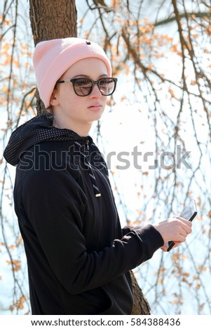  smiling teenager girl with pink hat and sun glasses  listen to music on a mobile