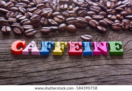 word caffeine and coffee beans on old wooden table