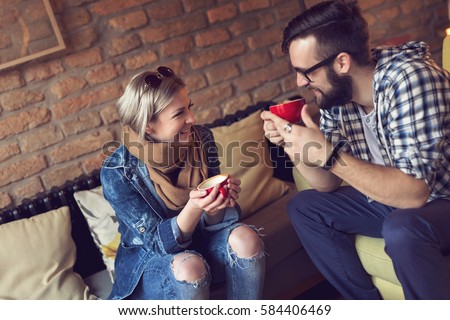 Young couple in love sitting in a cafe, drinking morning coffee and having a pleasant conversation. Focus on the girl Royalty-Free Stock Photo #584406469