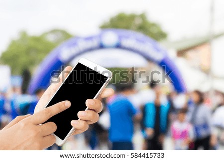 woman use mobile phone and blurred image of people in the marathon racing at finished point