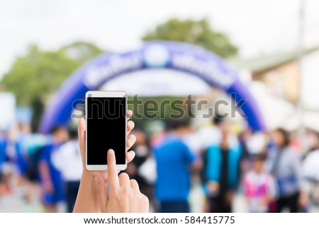 woman use mobile phone and blurred image of people in the marathon racing at finished point