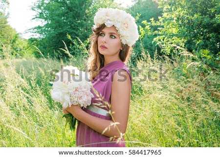 portrait of young beautiful curly woman in the peony wreath outdoor on green background