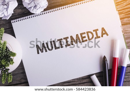 Notepad and green plant on wooden background with MULTIMEDIA word