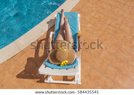 Top view of a woman in hat resting in the edge of a swimming pool