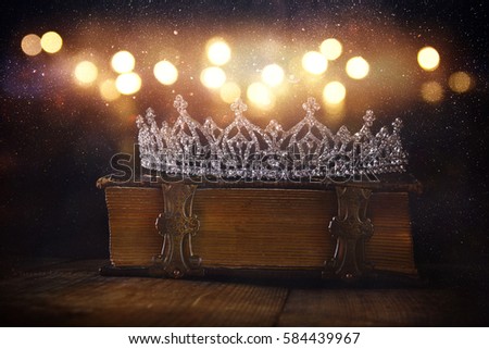 low key image of beautiful diamond queen crown on old book. vintage filtered. selective focus. medieval period concept