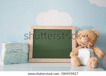 Diapers and blank chalkboard. Teddy bear dressed in diaper. frame with a copy space