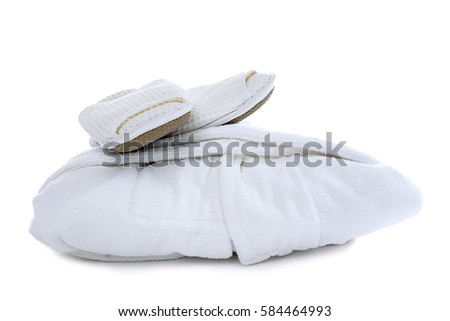 Folded spa bathrobe with slippers on white background