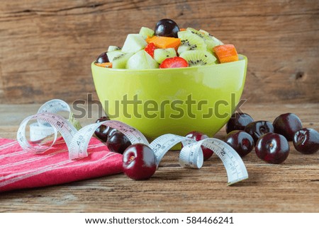 Fruit salad in the bowl with measuring tape on wooden table. with copy space for text.