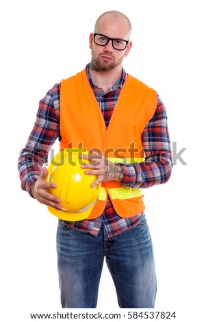 Studio shot of young bald muscular man construction worker standing while holding safety helmet