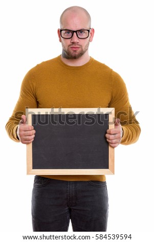 Studio shot of young bald muscular man holding blank blackboard
