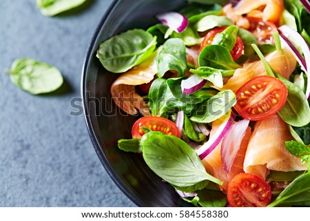 Salmon Salad with spinach, cherry tomatoes, corn salad, baby spinach, fresh mint and basil. Home made food. Concept for a tasty and healthy meal. Dark stone background. Top view. Close up.  Royalty-Free Stock Photo #584558380