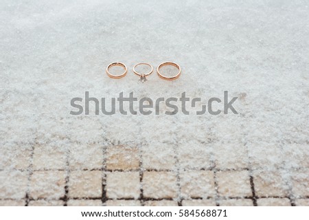 Wedding and engagement rings in gold on the snow