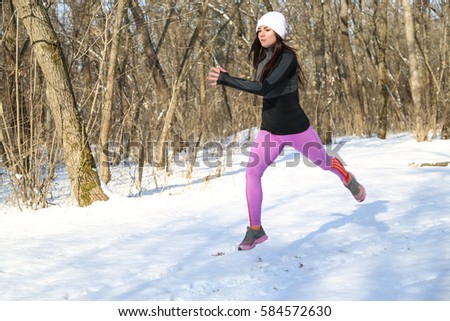 Running sport woman. Female runner jogging in cold winter forest wearing warm sporty running clothing and gloves headphones. Beautiful fit  female fitness model.