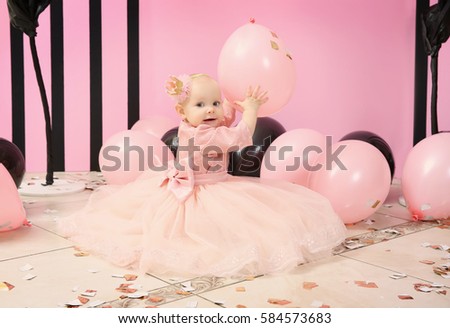 Cute little birthday girl playing with balloons at party