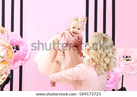 Mother with cute baby girl in room decorated for birthday party