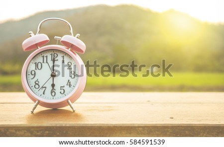 Clock on wood in the morning, blurred nature background. Royalty-Free Stock Photo #584591539
