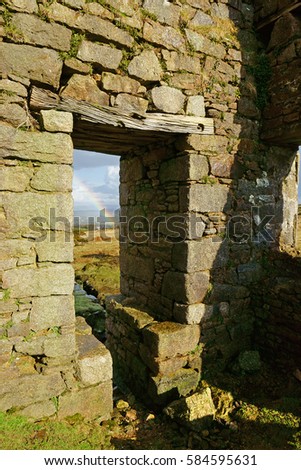 Looking from inside the ruins of the Wheal Jenkins mine shaft at a partial rainbow in winter on Caradon Moor which is part of Bodmin Moor, Cornwall, England, UK