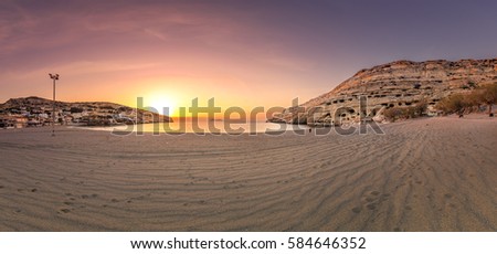 Panorama of Matala beach at sunset with the caves on the rocks that were used as a roman cemetery and at the decade of 70's were living hippies from all over the world, Crete, Greece
