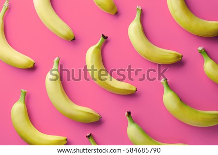 Colorful fruit pattern of fresh yellow bananas on pink background. From top view