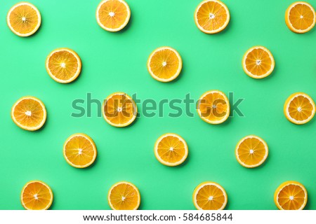 Colorful fruit pattern of fresh orange slices on green background. From top view Royalty-Free Stock Photo #584685844