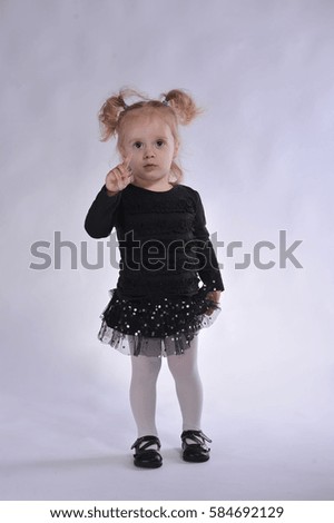 The little blonde girl dressed in black played on a photo shoot in a white photo studio