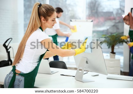 Young female worker cleaning office Royalty-Free Stock Photo #584700220