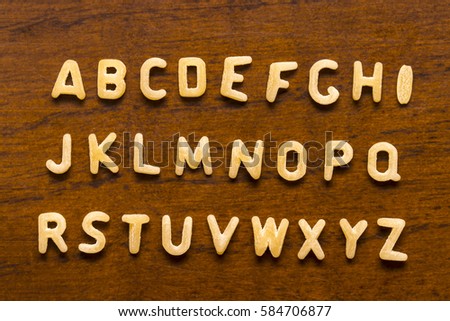 Alphabet made of macaroni letters isolated on wood background. Royalty-Free Stock Photo #584706877