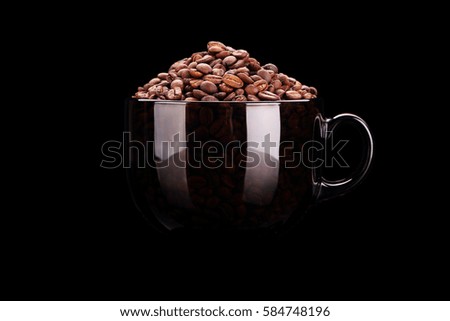 Cup with coffee beans on black background