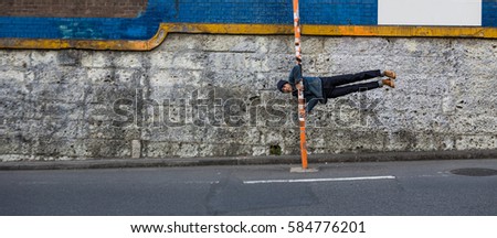 Asian man make the perfect human flag with traffic sign pole on street.