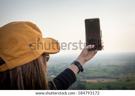 Woman enjoying in nature and taking picture in the mountain with mobile phone.