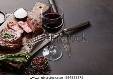 Grilled ribeye beef steak with red wine, herbs and spices on stone table