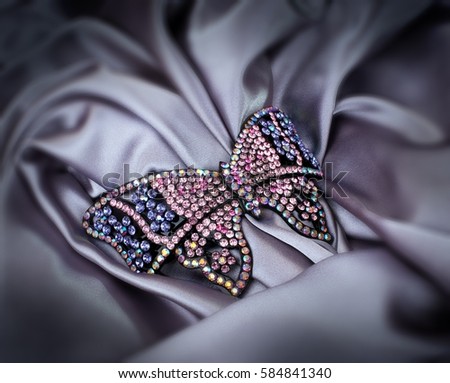 Stone fitted butterfly hair clip on grey drapery Royalty-Free Stock Photo #584841340