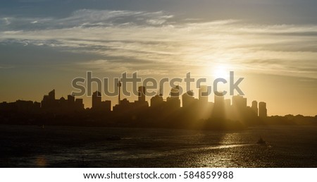 The city of Sydney at sunset with the buildings in silhouette.